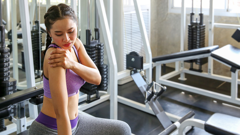 Fit woman having shoulder pain while in the gym