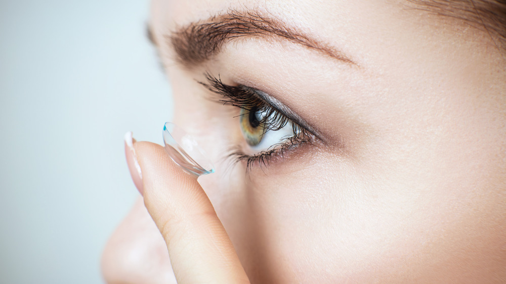 Close up of woman putting a contact lens in her eye