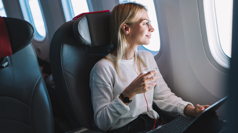 Woman holding cup of water on plane