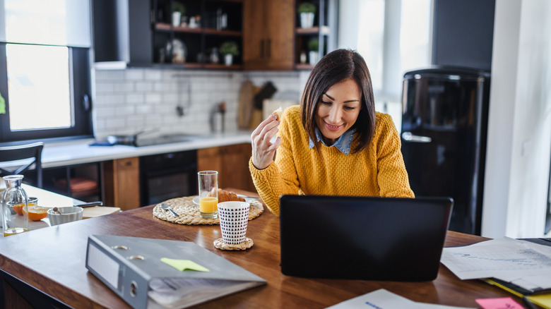 A woman eats breakfast with a glass of orange juice