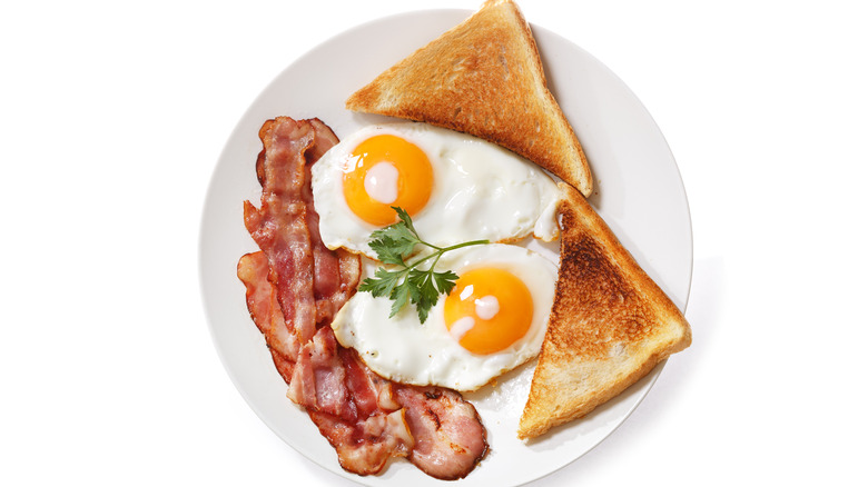 Fried eggs, toast, and bacon on a plate