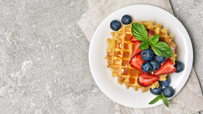 A waffle on a plate topped with fresh fruit