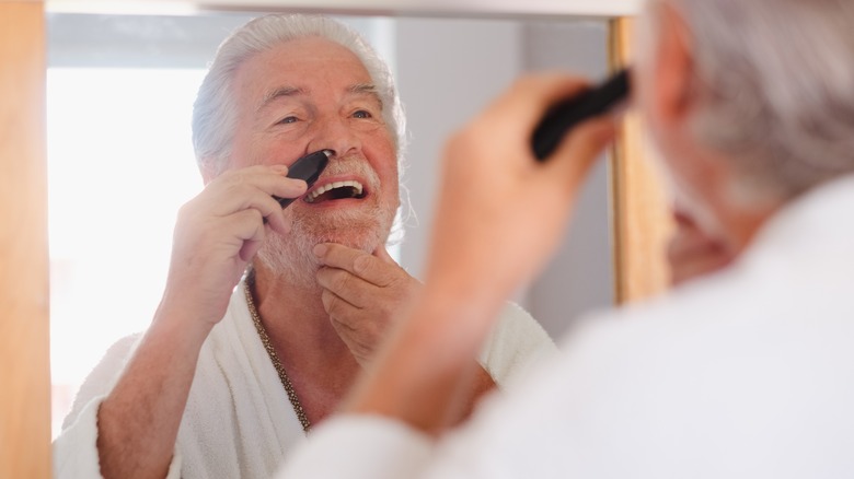 Older man using nose trimmers