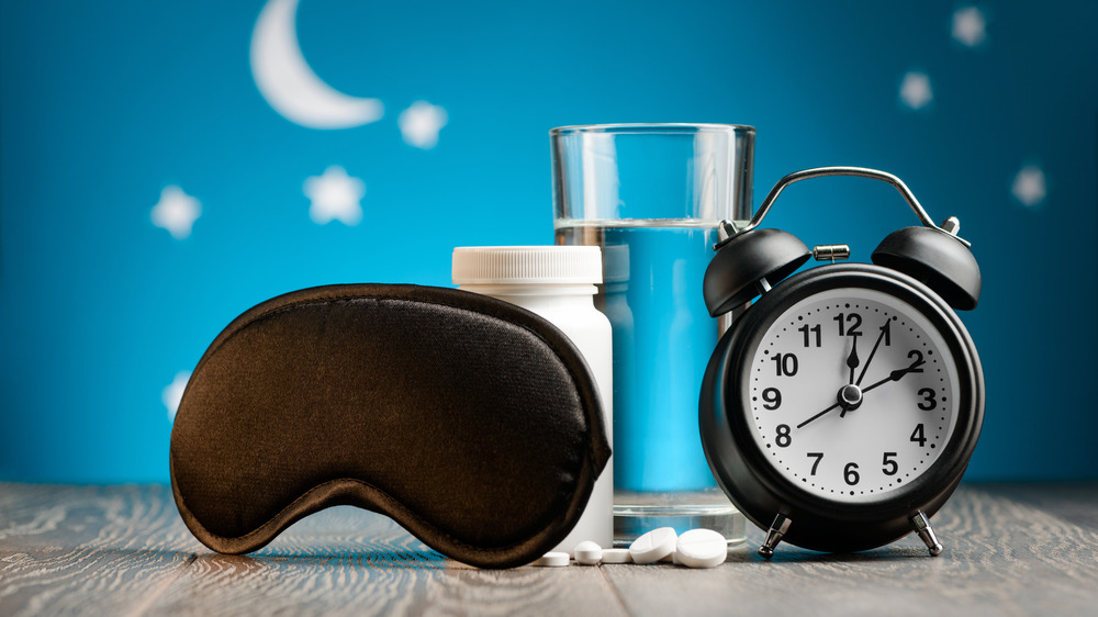Sleep mask, pill bottle, water and alarm clock
