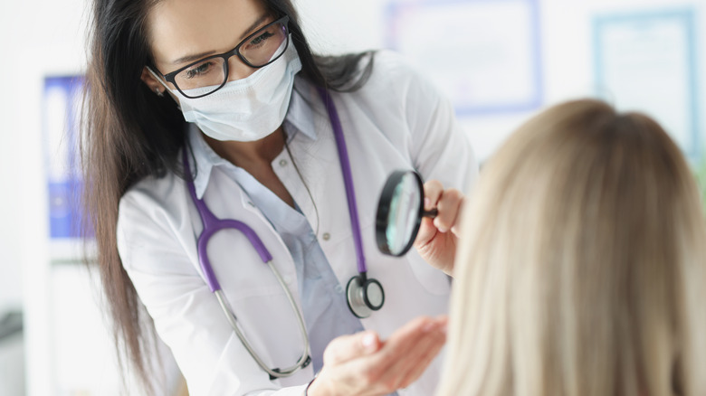 Dermatologist examines patient's face