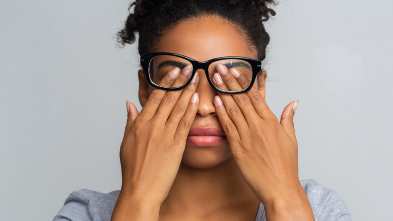 woman with glasses rubbing her eyes