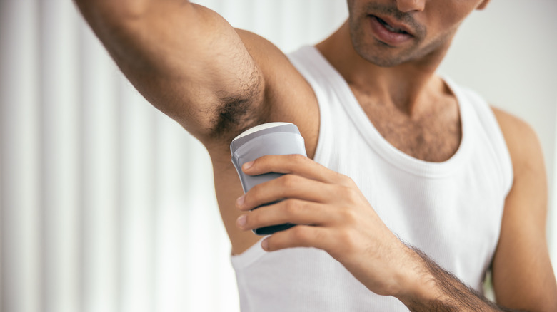 man applying deodorant to underarm