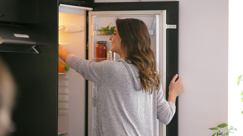 Woman reaching into refrigerator 