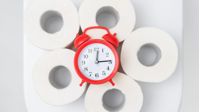 A table clock on top of toilet paper rolls