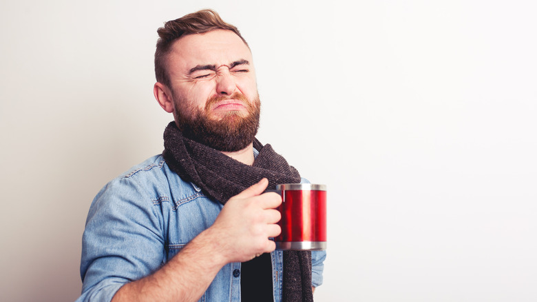 grimacing man holding a cup of coffee