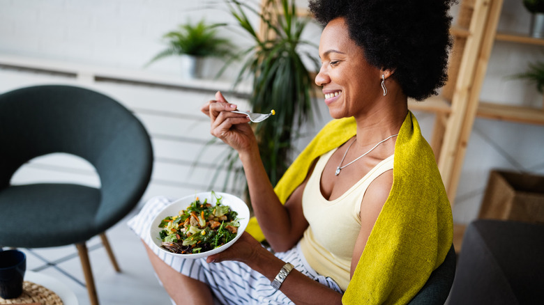 Woman eating salad on couch