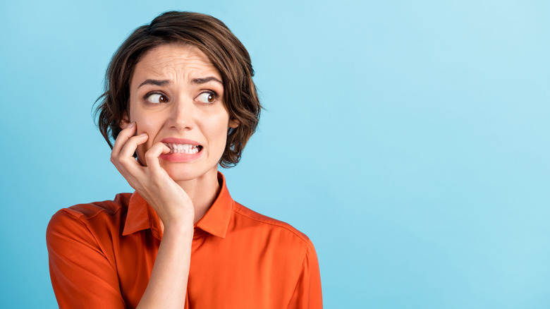 A woman bites her nails nervously