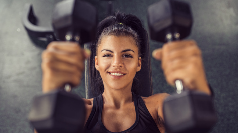 woman lifting dumbbells on her back