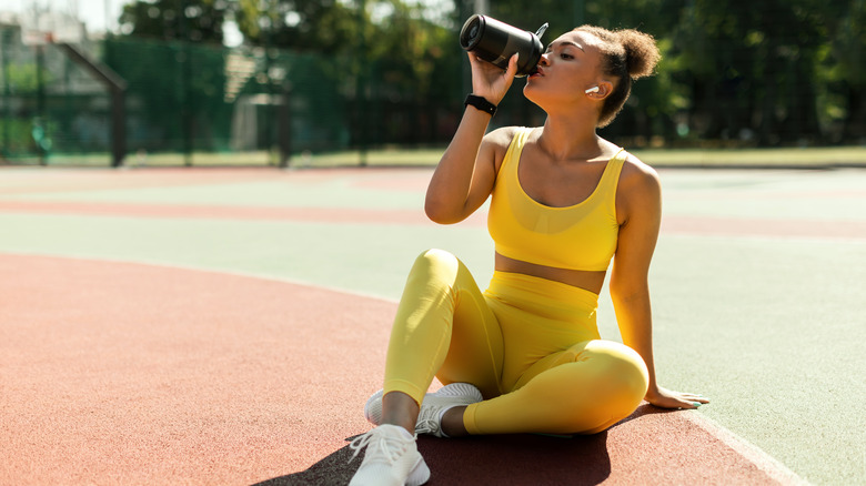 Woman in yellow activewear drinking 