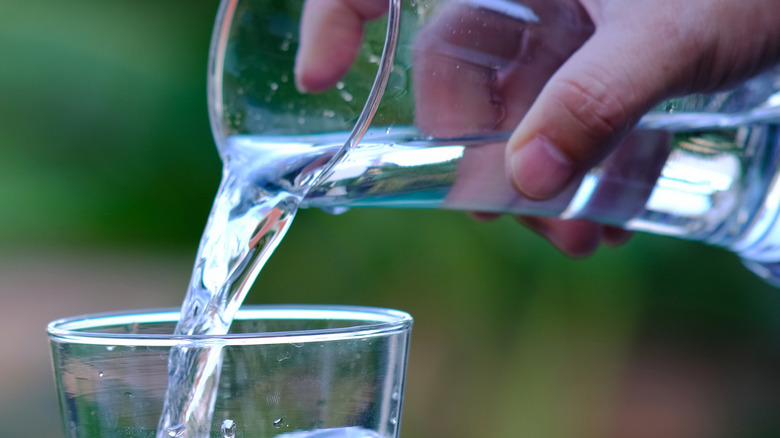 Hand pouring water into another glass