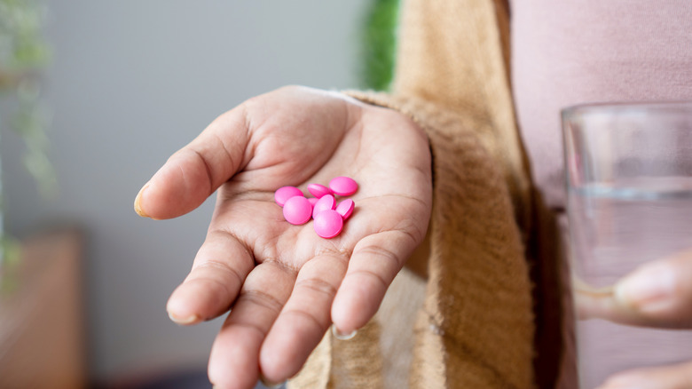 woman's hand holding ibuprofen pills