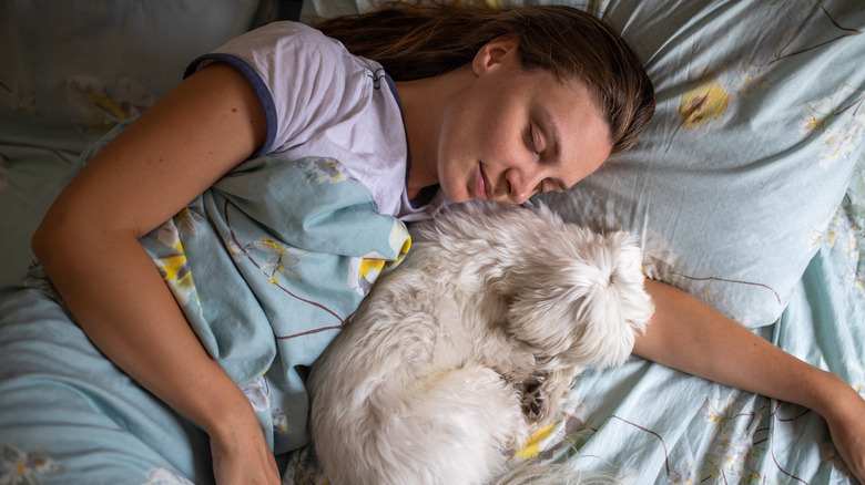 woman sleeping in her bed with her dog