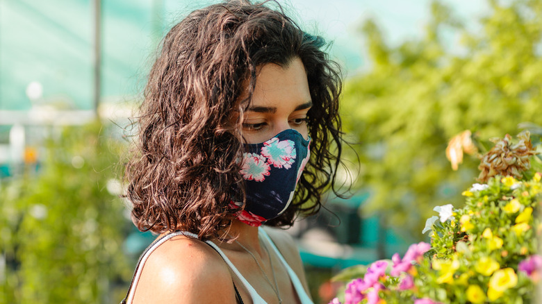 woman wearing a mask while handling flowers