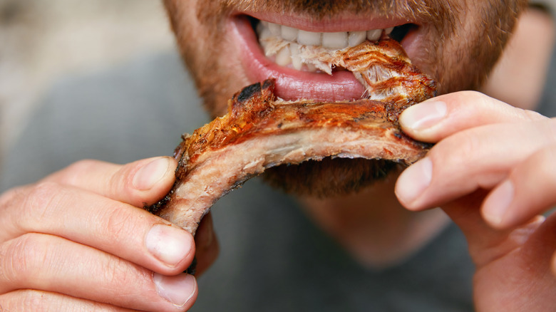 man biting into rib meat