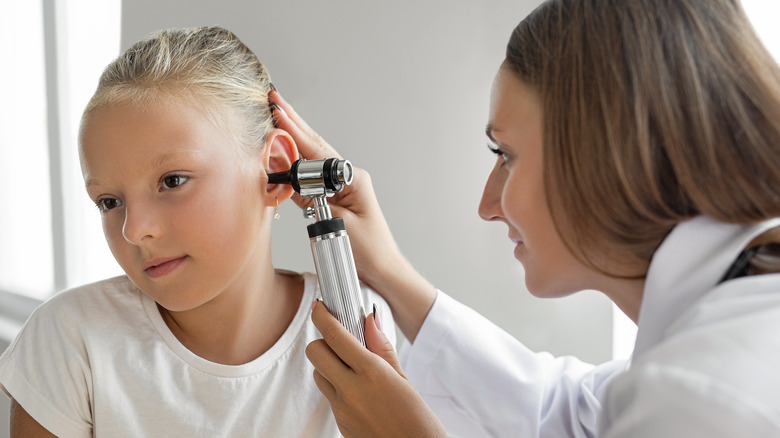 Doctor examining young girl's ear