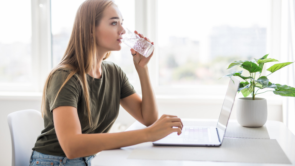 woman drinking water at desk