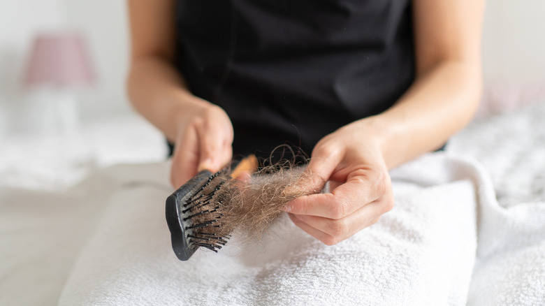 Woman removing hair from hairbrush