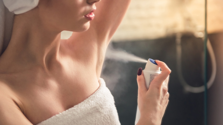 woman putting antiperspirant on armpit