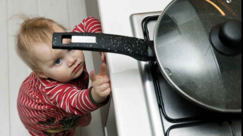 toddler reaches for hot pot on stove