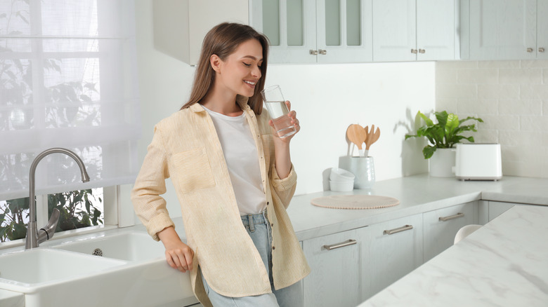 Woman drinking water in kitchen