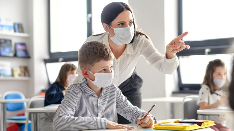 child with a teacher wearing masks