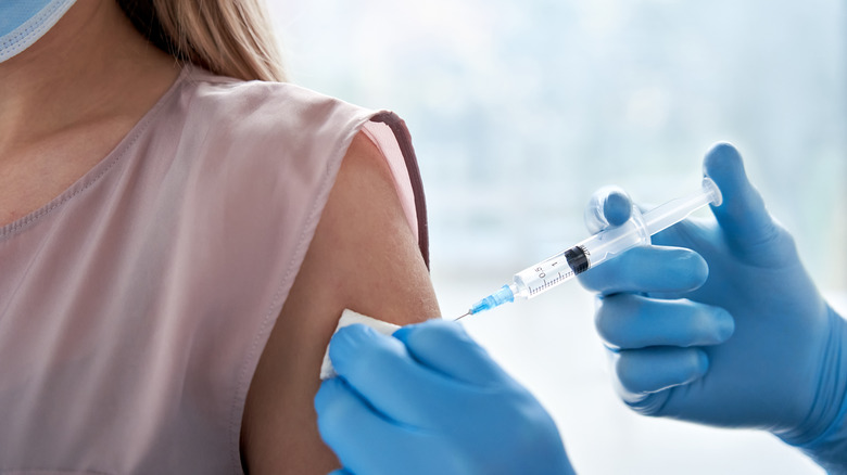 Doctor holding syringe giving COVID-19 vaccination injection dose in arm of patient