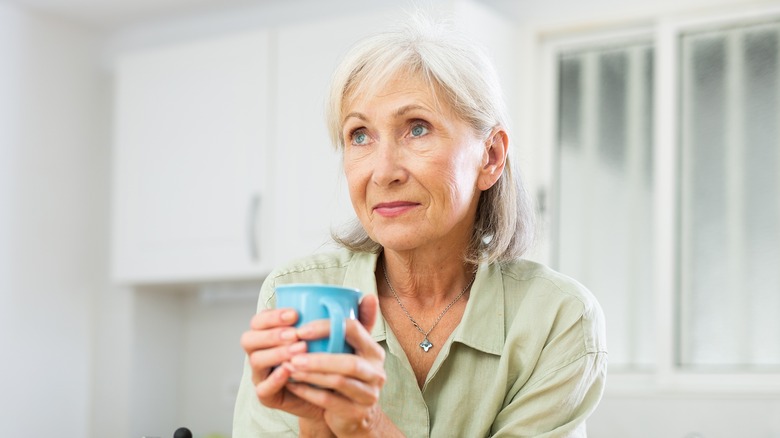 woman holding a cup while looking into the distance