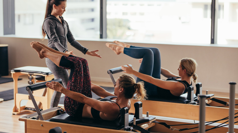 Two women working out on Pilates reformers