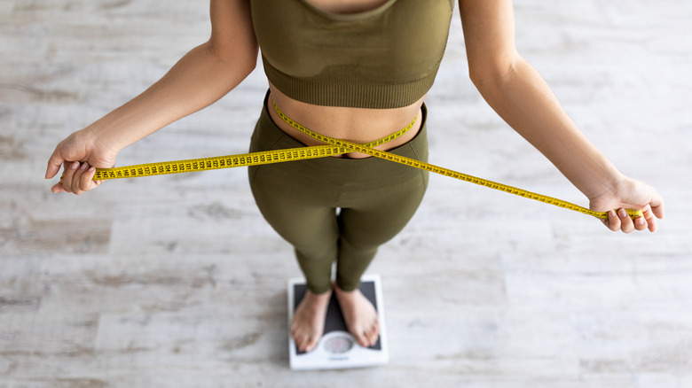 woman standing on scale with tape measure