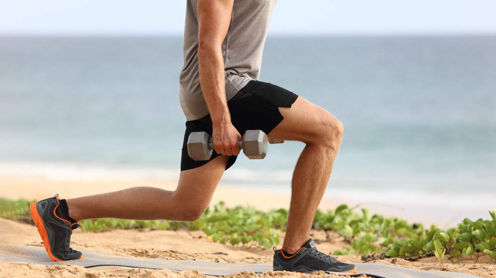 Close up of man's legs in a lunge pose at the beach