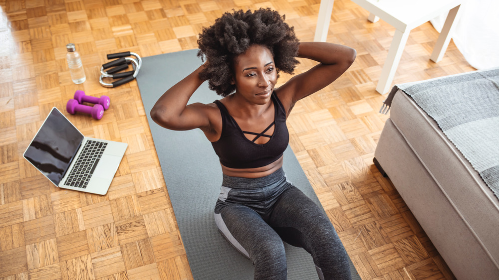 Woman doing situps on her yoga mat at home