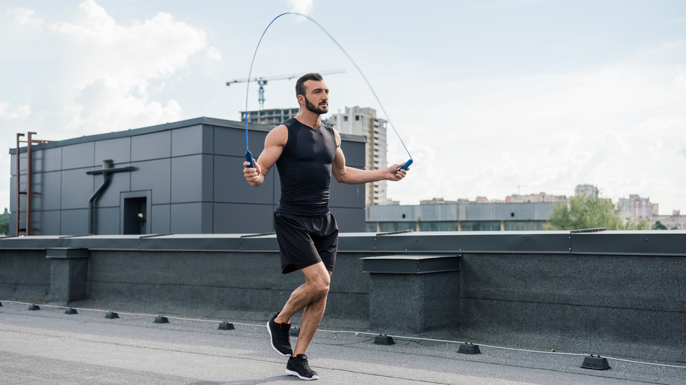 Man in a tank top jumping rope outdoors