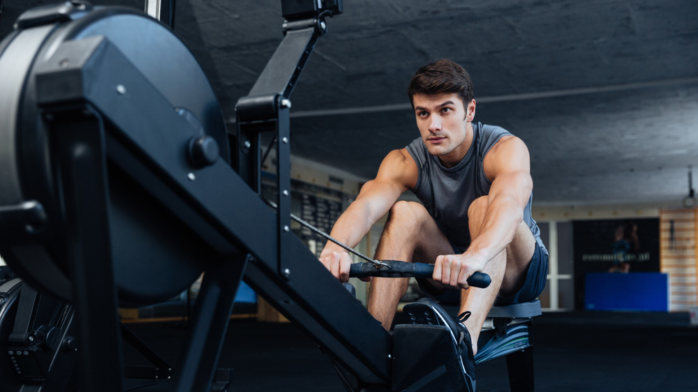 Man in a tank top using a rowing machine at the gym