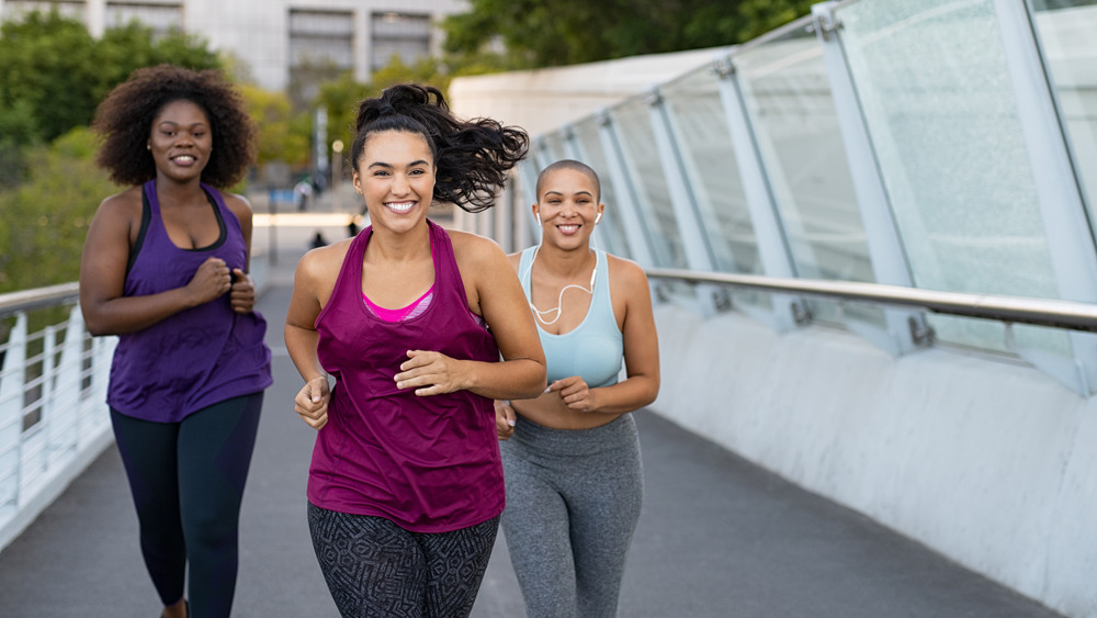 Three women smiling and running for exercise outside