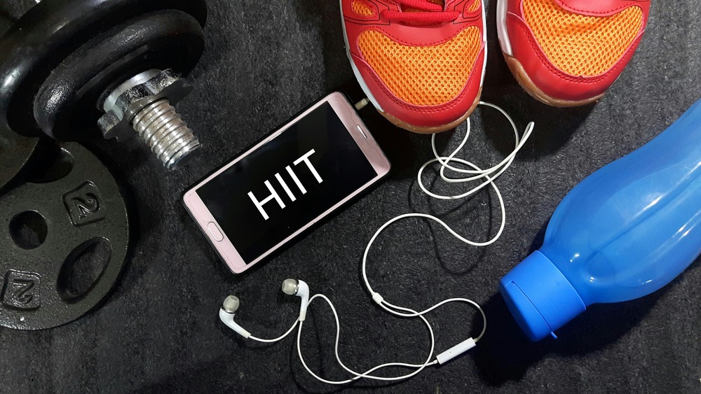A cellphone with the acronym HIIT on it surrounded by workout gear