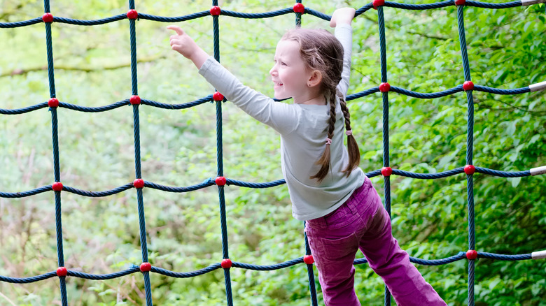 kid climbing obstacle net outside