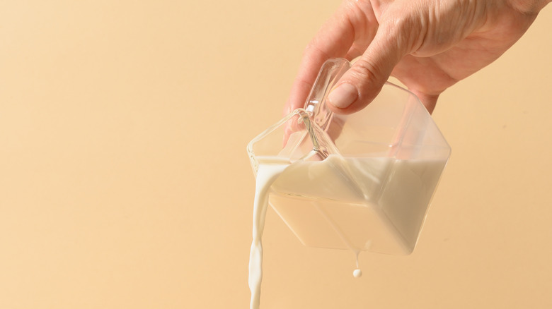 Milk being poured into a glass of coffee