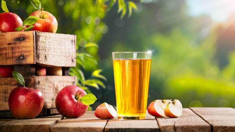 A glass of apple juice by apples