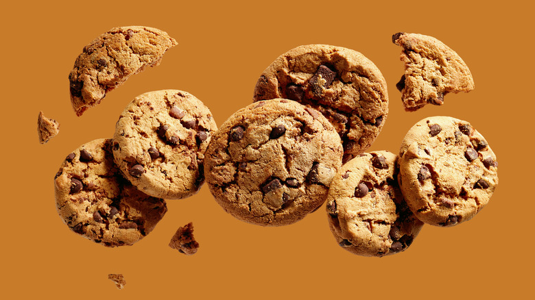 Chocolate chip cookies in mid air against a brown background