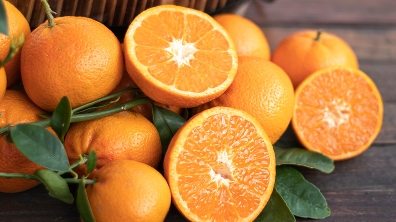 Oranges with green leaves on wooden surface