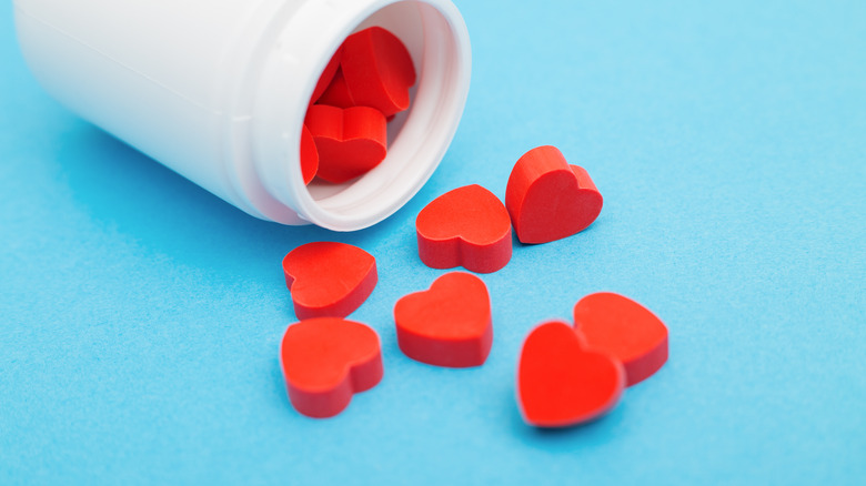 A bottle of heart-shaped pills spilled out against a light blue surface