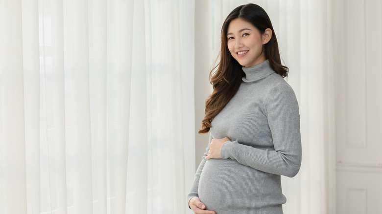 Pregnant woman holding her stomach and smiling