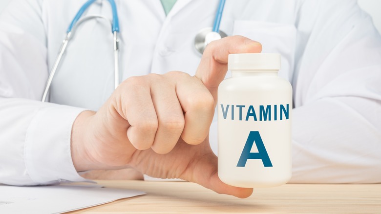 Doctor holding a bottle that says "vitamin A"