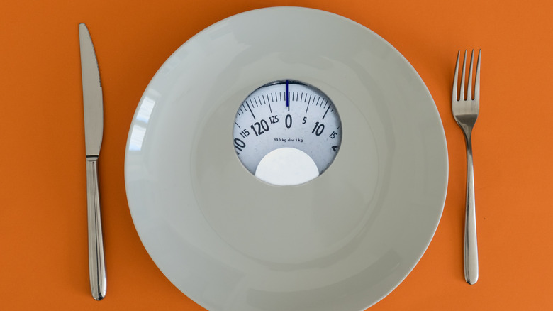 A white plate crossed with a bathroom scale 