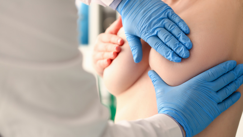 gloved hands examining female breasts